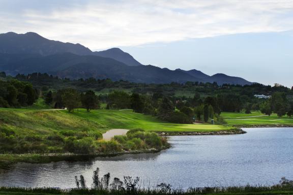 A pond on the Country Club of Colorado's golf course. Mountains are visible in the background of the photo.
