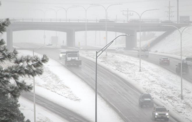 Cars drive on the road during a heavy snow storm.