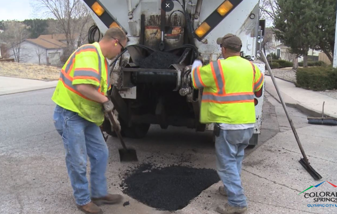 two men fill pothole